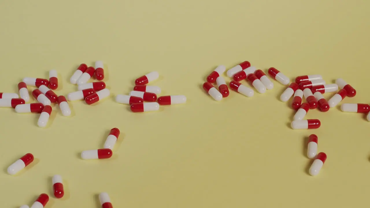 Slow motion high-angle medium shot as a handful of pills fall vertically