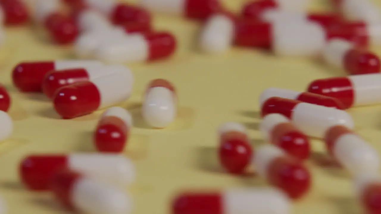 Slow motion close-up of a single pill as several pills roll by and push it out of frame