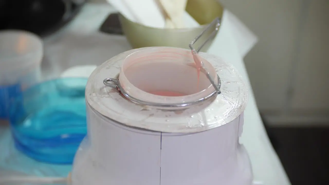 Cose up of a beautician preparing for leg waxing by applying wax to a spatula from a wax pot