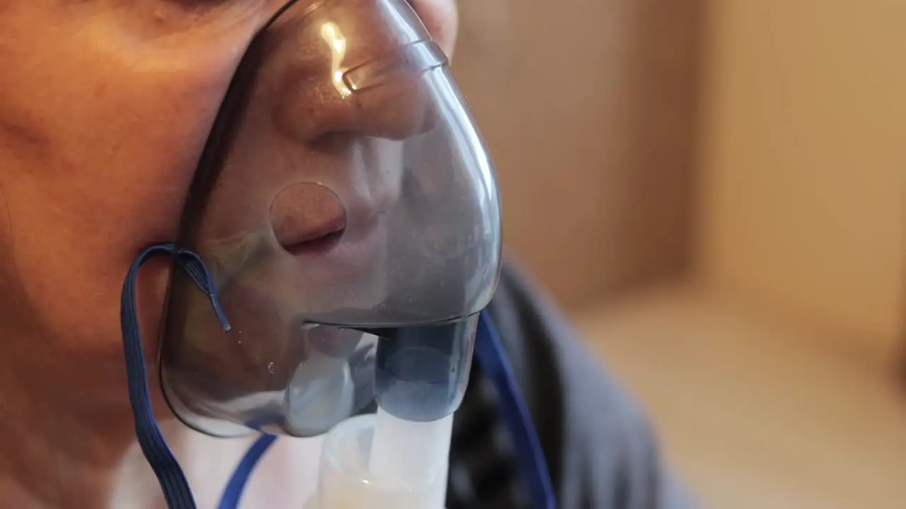 Extreme close up shot of an older woman using a respiratory mask inhaling medicine to clear out her throat and sinuses