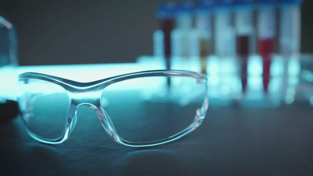 Laboratory workstation with glass safety goggles measuring vessels and sample tubes on a bluish table