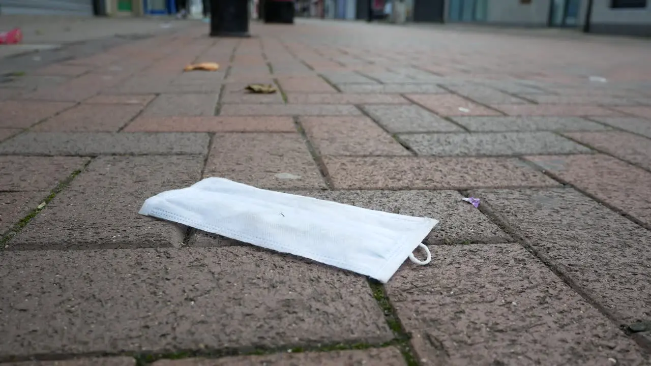 Corona virus face mask trash on the floor in quiet city brickwork street