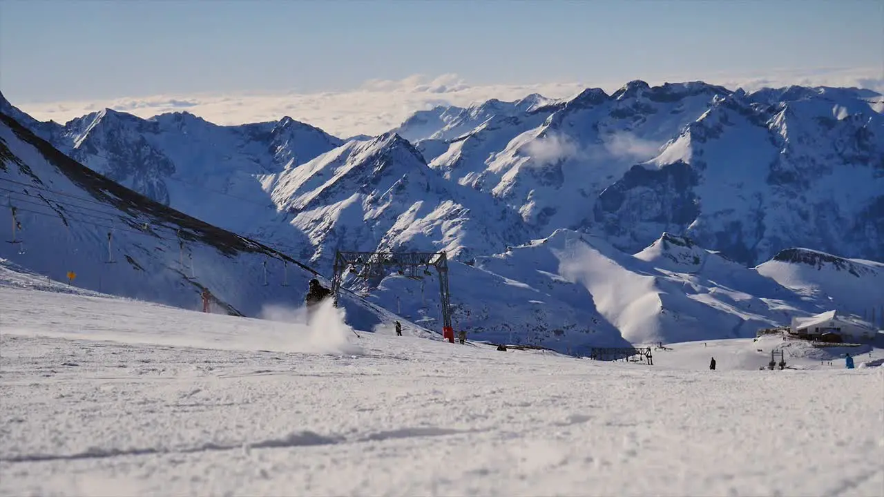 unrecognizable single skier passing by the camera spraying snow with mountain view on a sunny day with blue skies