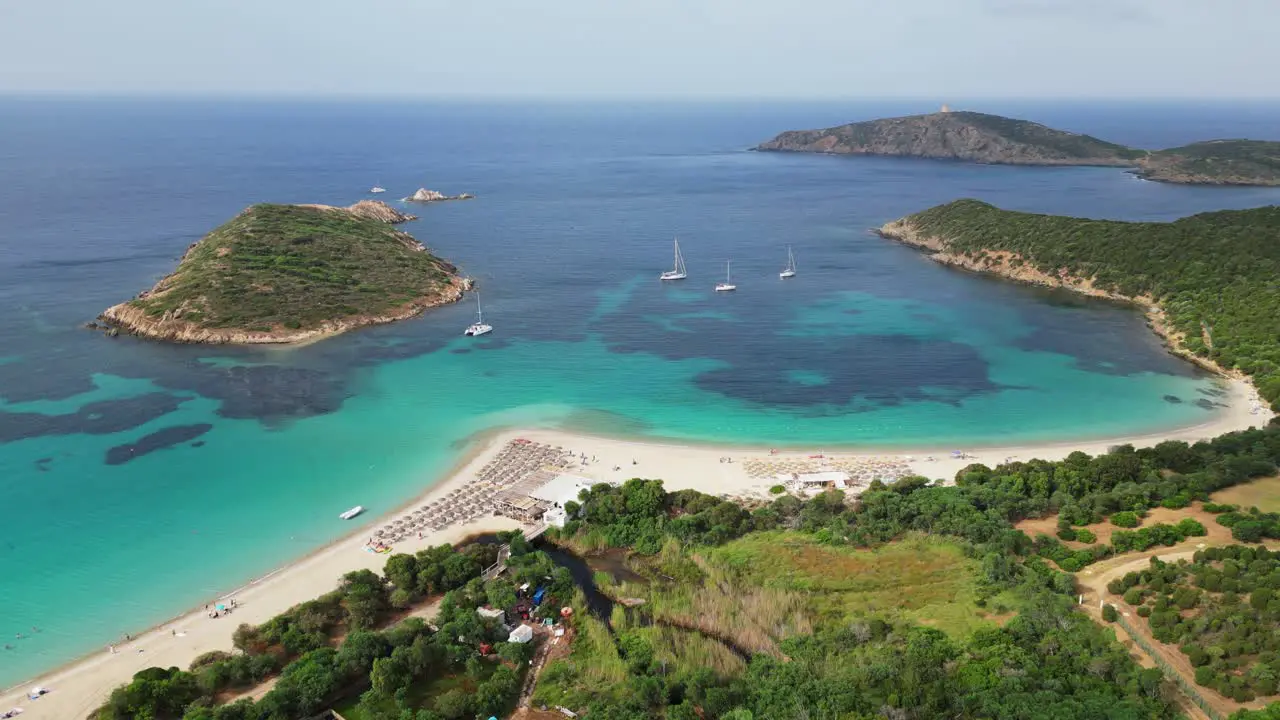 Turquoise blue bay with sandy Tuerredda beach boats and islands in Teulada Sardinia Italy 4k Aerial Circling