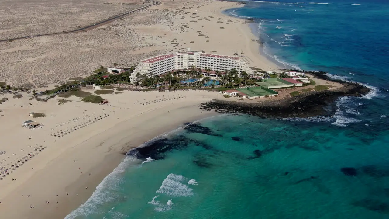 drone shot in orbit over hotel complex in and over the sea corralejo beach Fuerteventura canary islands