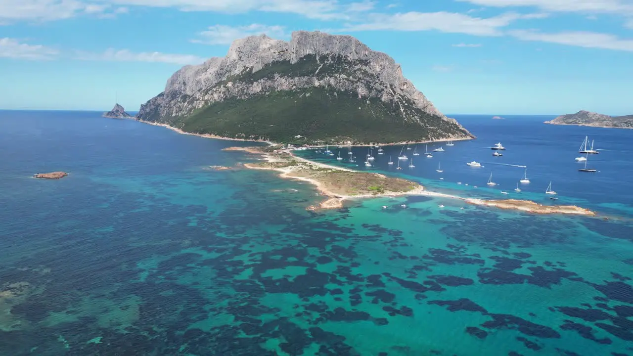 Tavolara Island surrounded by boats and turquoise blue sea during summer in Sardinia Italy Aerial 4k