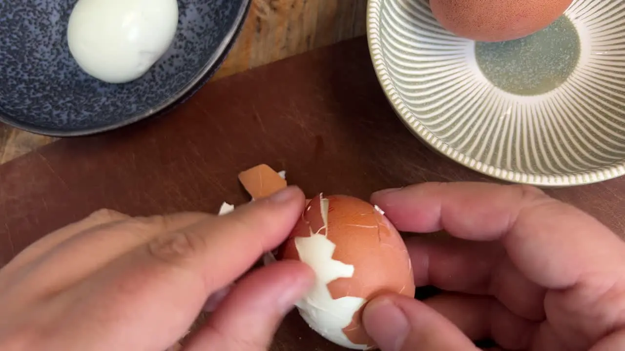 Peeling hard boiled eggs close up