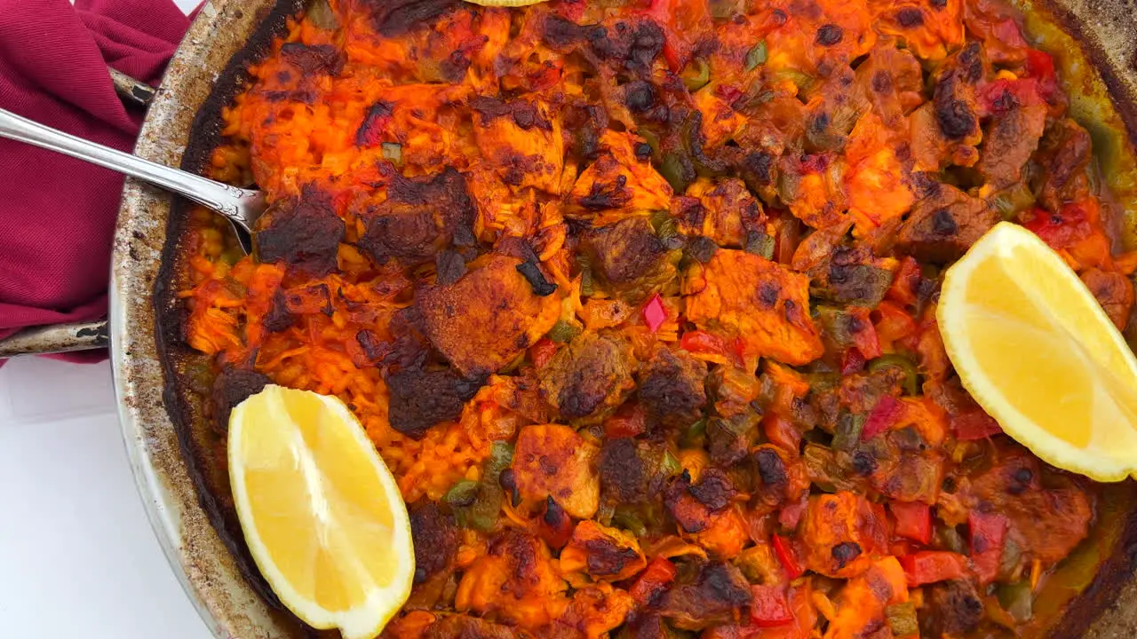 Traditional Spanish Paella dish with chicken vegetables and lemon slices in a restaurant seafood with rice in Marbella Spain 4K shot