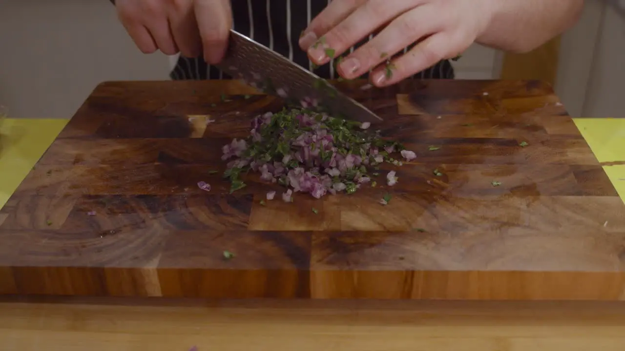 Chef chops onion and herbs on a cutting board