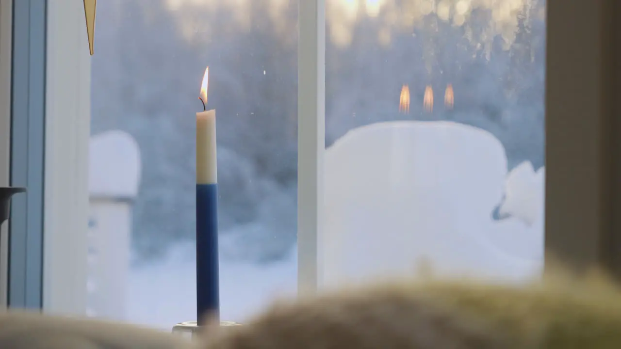 lit blue and white candle by window for Finland Independence Day