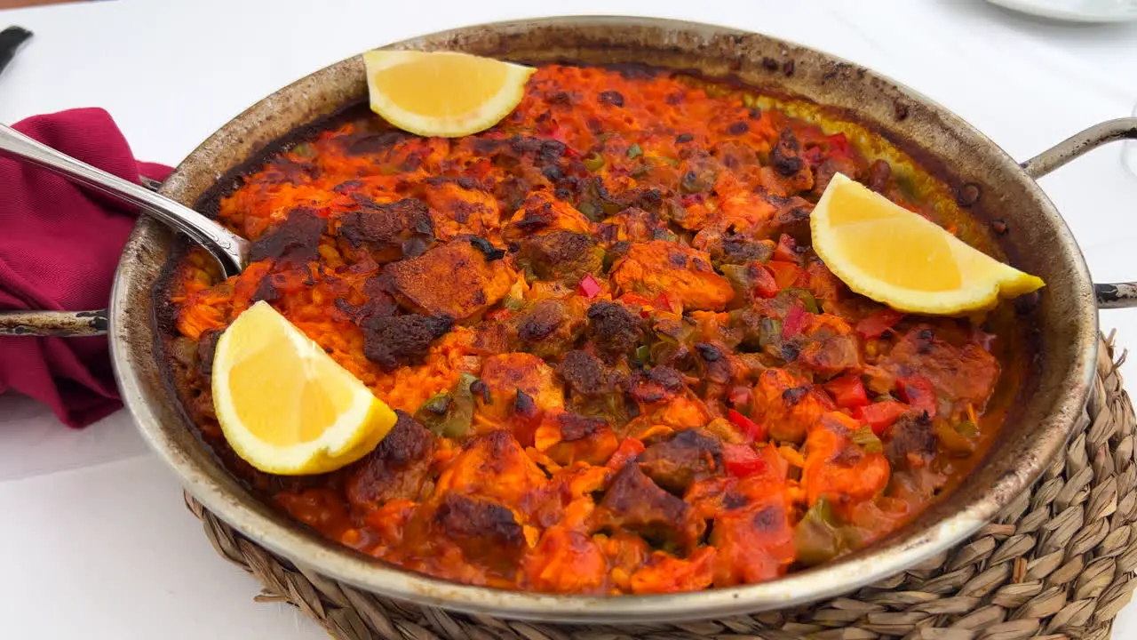 Traditional Spanish Paella dish with chicken vegetables and lemon slices in a restaurant seafood in Marbella Spain 4K shot