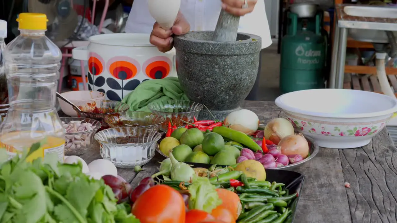 Chef using large stone mortar and pestle to crush and prepare ingredients