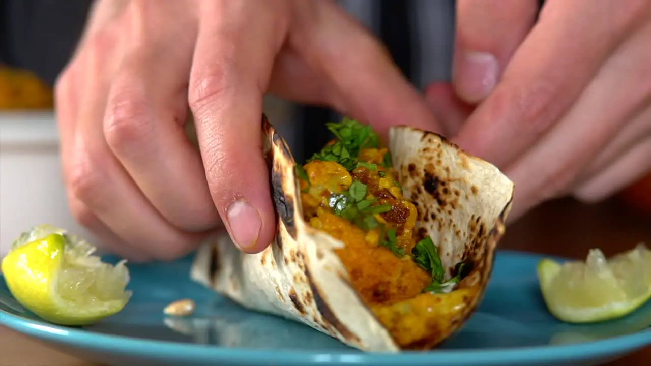 Man takes a colorful taco fold it and bring it away from the frame so he can eat it