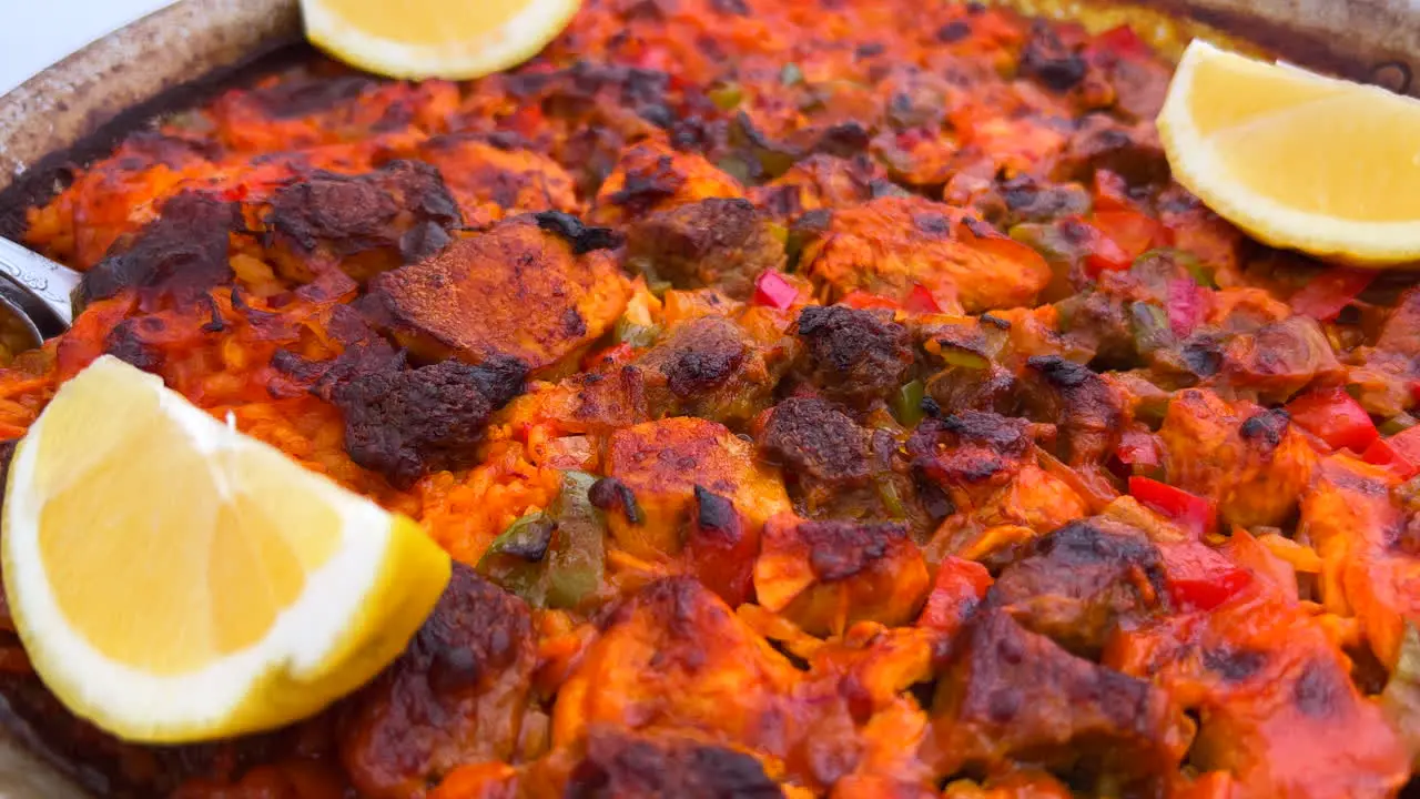 Traditional Spanish Paella dish with chicken vegetables and lemon slices in a restaurant delicious seafood in Marbella Spain 4K shot