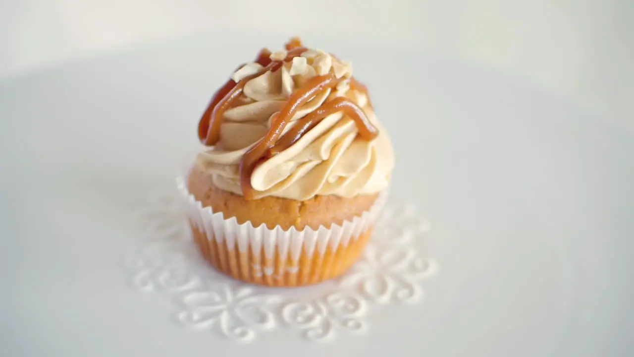 One peanut flavor muffin cupcake rotating slowly on decorated white plate