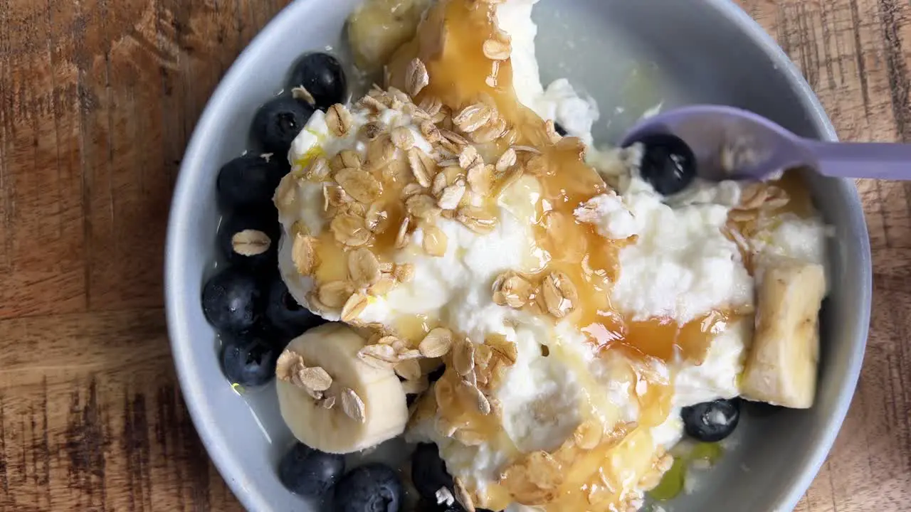 Eating breakfast with blueberries banana yoghurt and oats with some honey