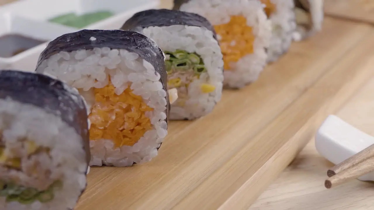 Slider Dolly Shot of Sushi on a Wooden Sering Platter with Chopsticks