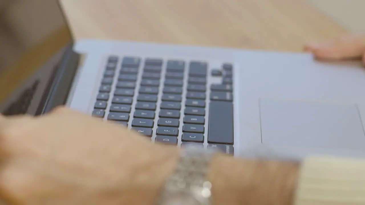 A close up of a man's hands as he pulls out a laptop starts typing and then puts it away