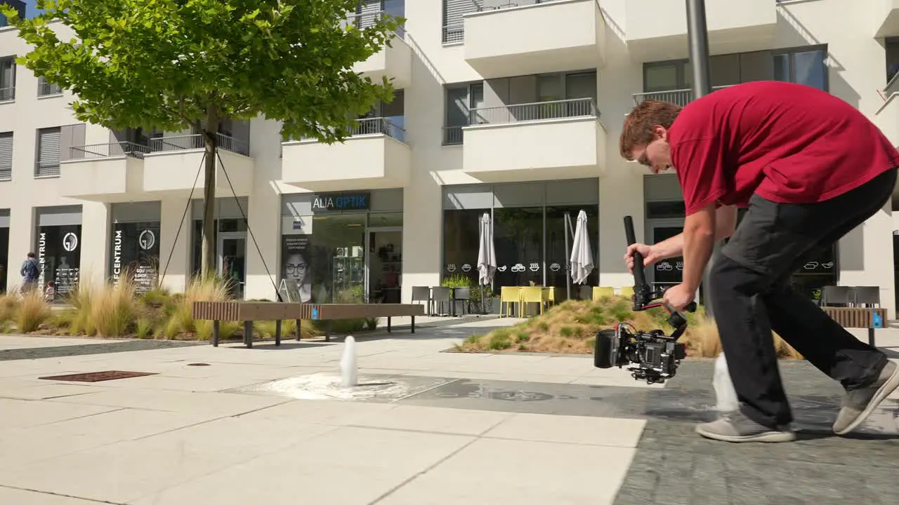 Young Man With Gimbal and Camera Shooting Low Angle Video Scene in City Exterior 50fps