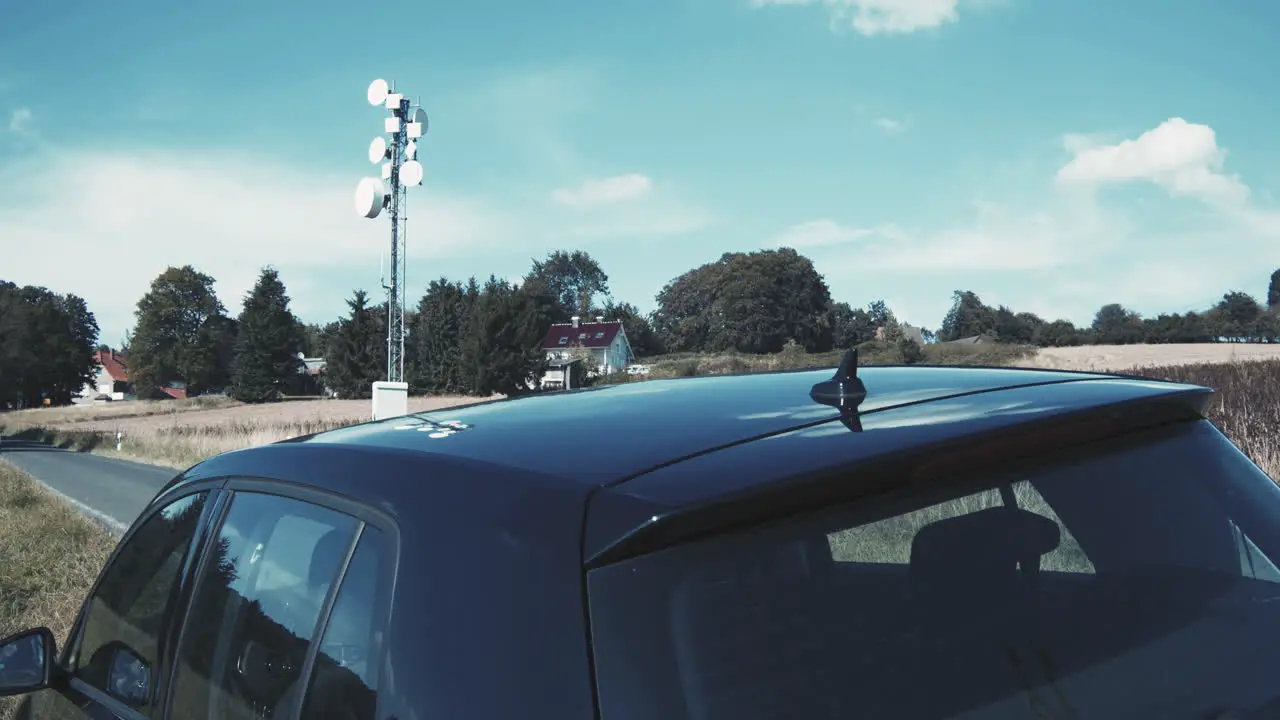 Black car with network communication mast for automatic driving and steering of the car in the background