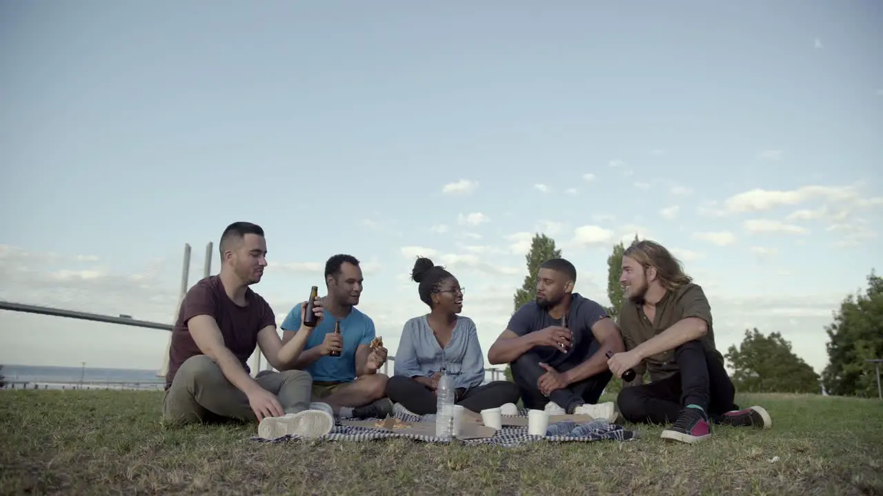 Happy people talking and drinking beer during picnic