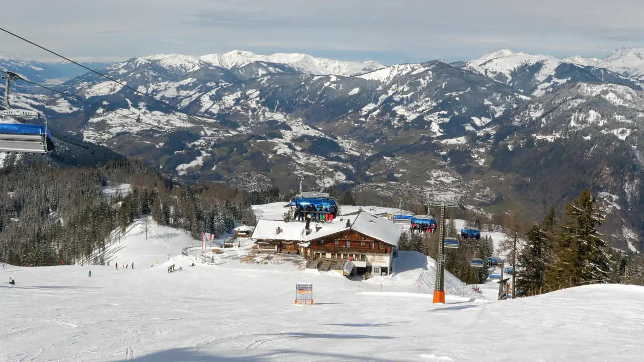 Medium wide shot of cable cars moving uphill and downhill at Wagrain on a bright sunny day with beautiful snow covered mountains in the background