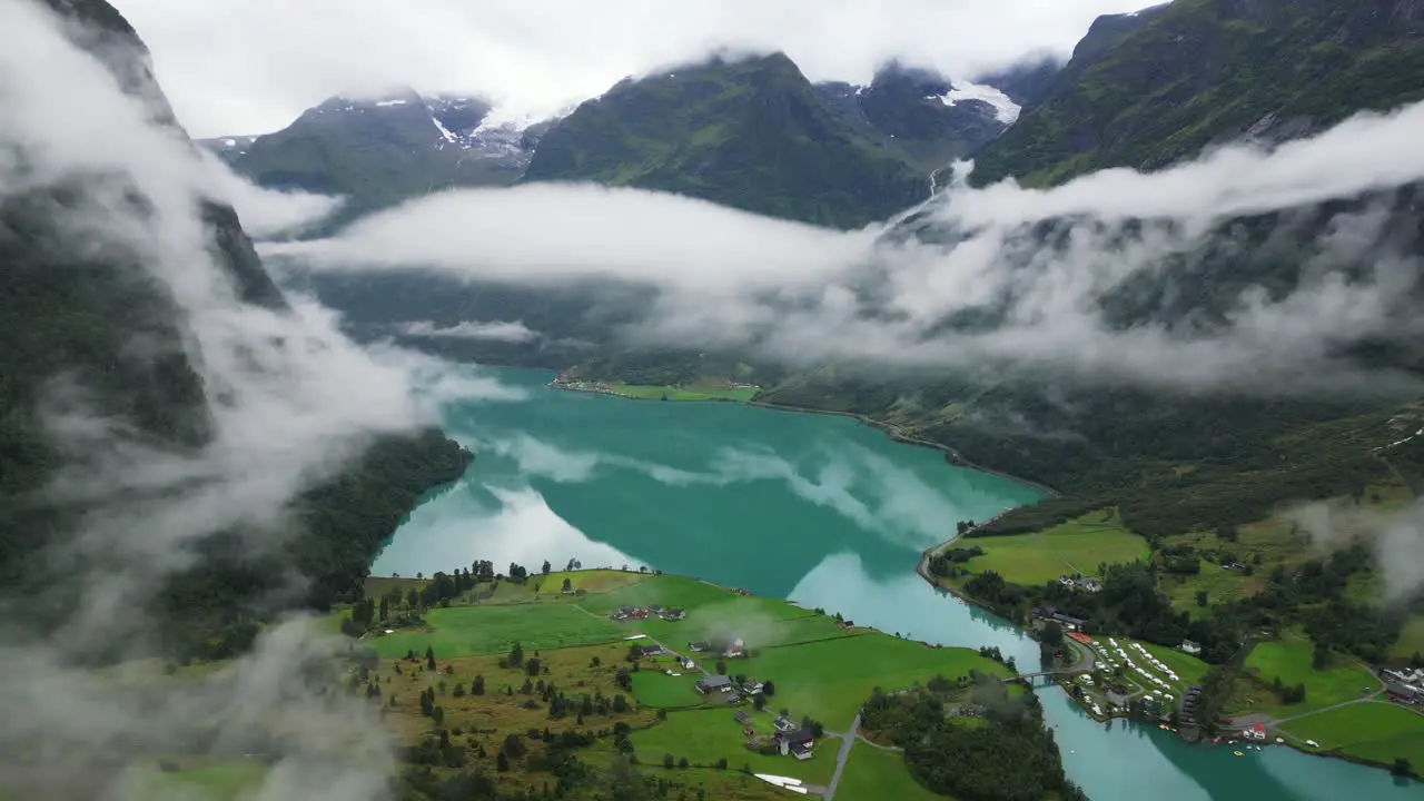 Oldevatnet Glacier Lake and Mountain Valley covered in clouds in Norway Loen Vestland Aerial Circling