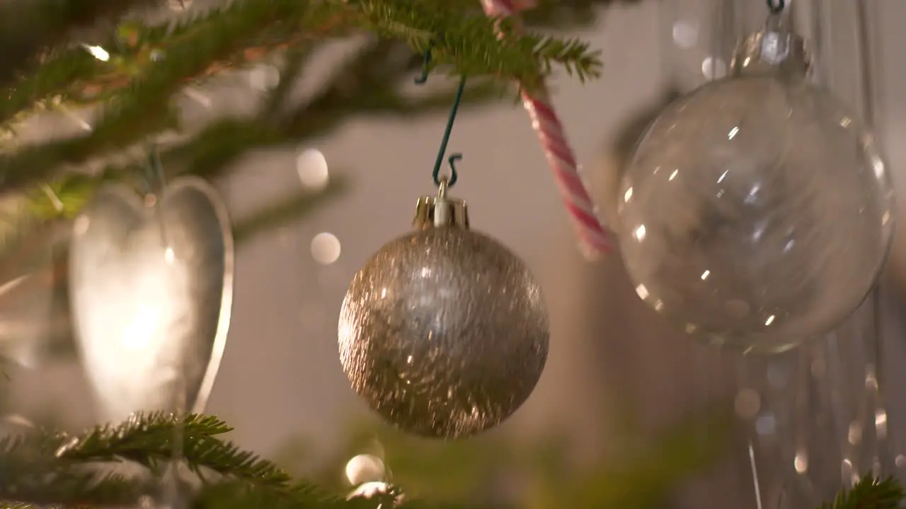 Real fresh-cut Christmas tree decorated with glitter ornaments and glass baubles close sliding dolly shot