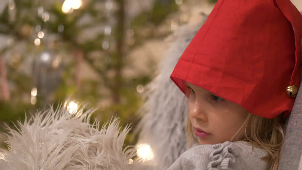 Cute little Girl with Santa hat sitting in front of a Christmas Tree Close up