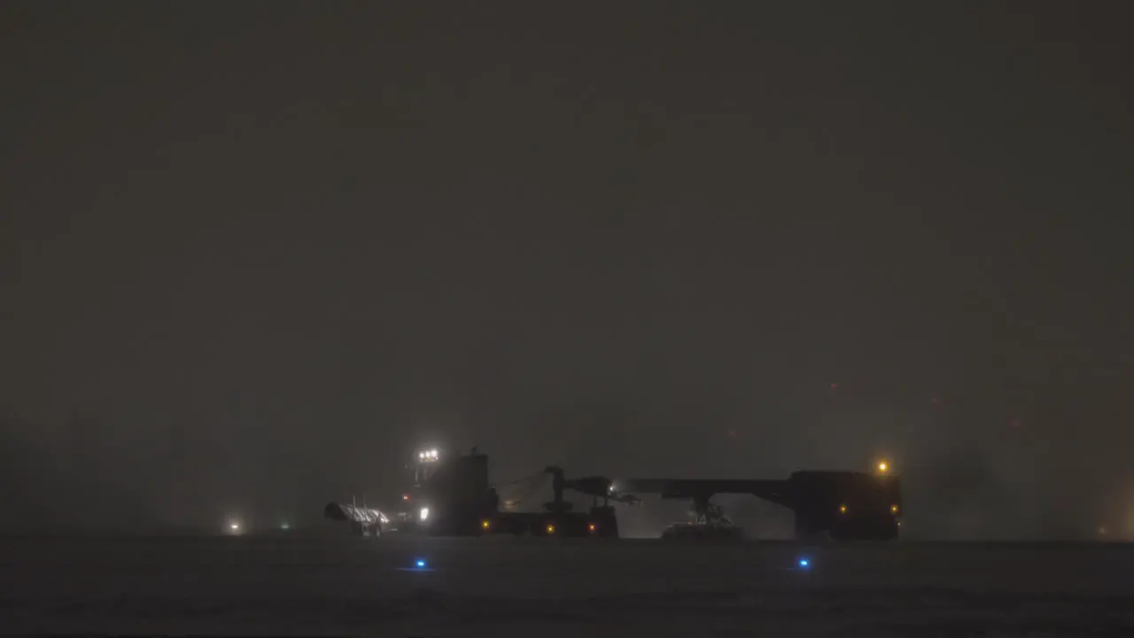 Snow plough cleaning runway in airport at night