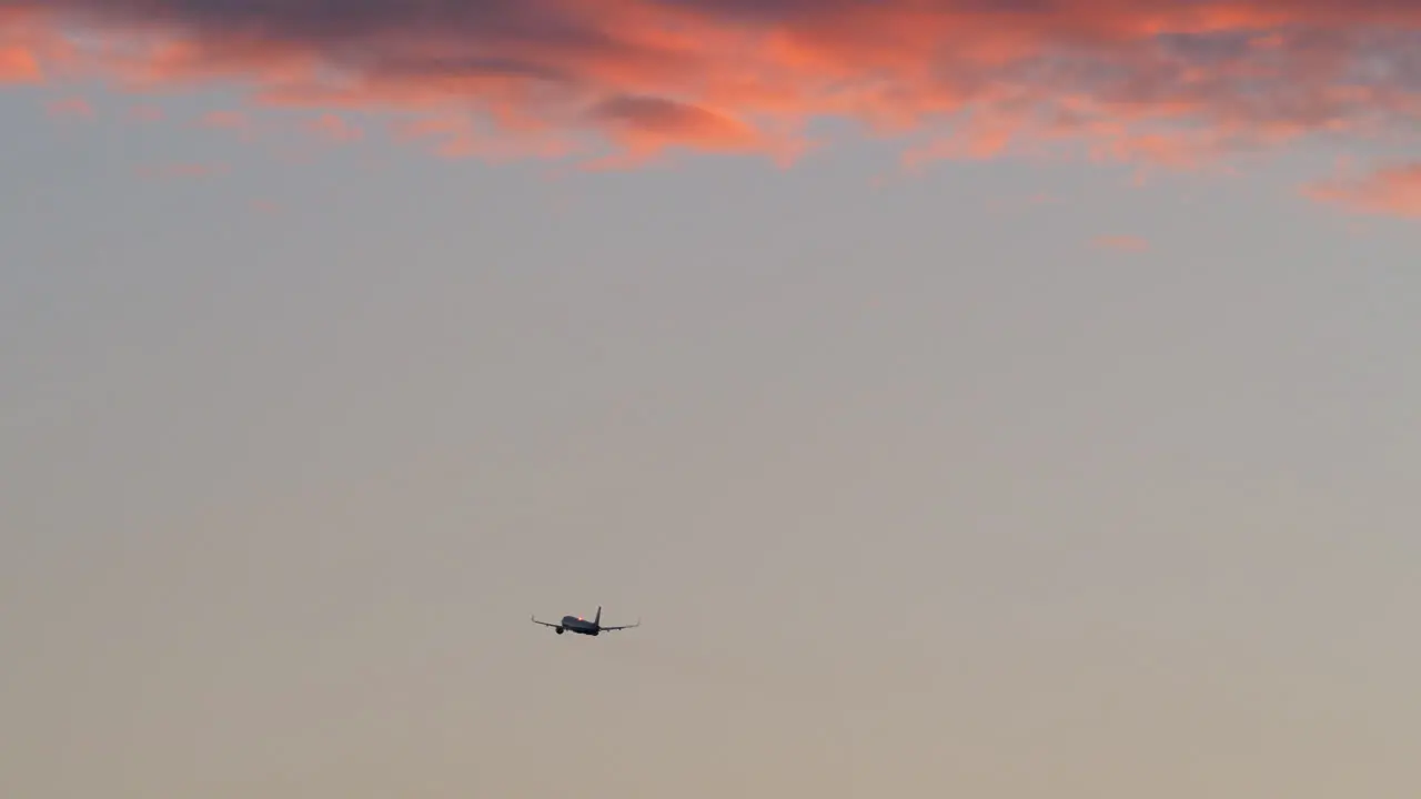 Airplane flying in evening sky with red clouds