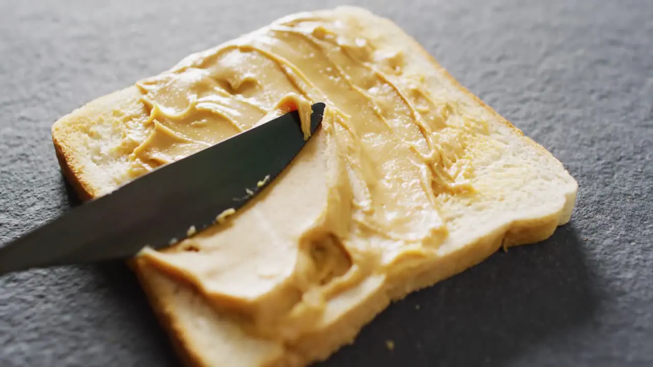 Video of close up of toast with peanut butter on gray background