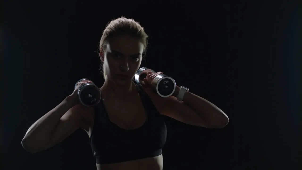 Fit girl posing with dumbbells on shoulders