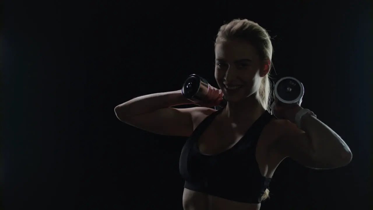 Fit woman posing with dumbbells in hands