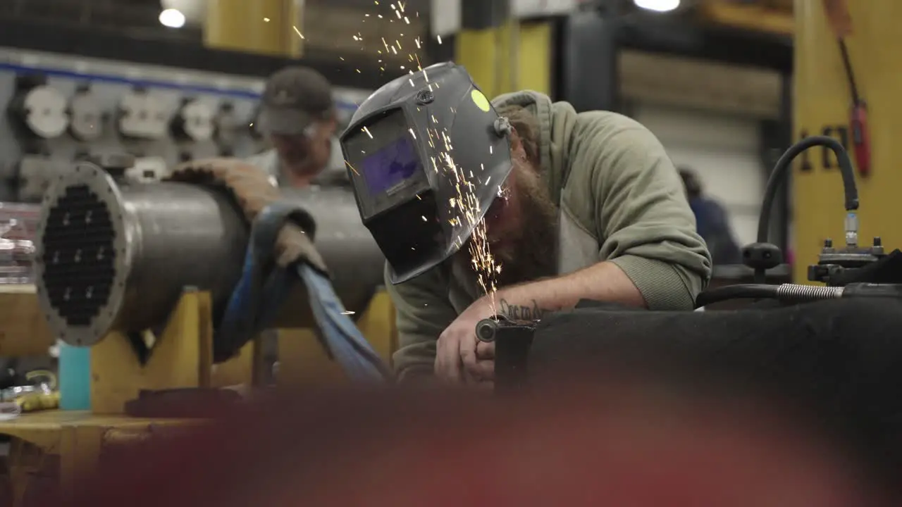 Blue collar worker grinding metal in industrial workshop slow motion