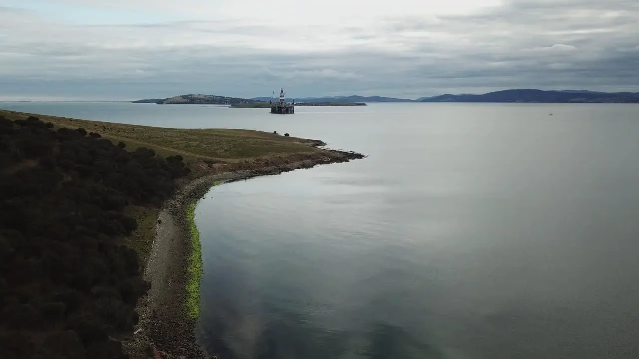 Drone PAN Around Rocky Coast With Oil Rig In Background Australia