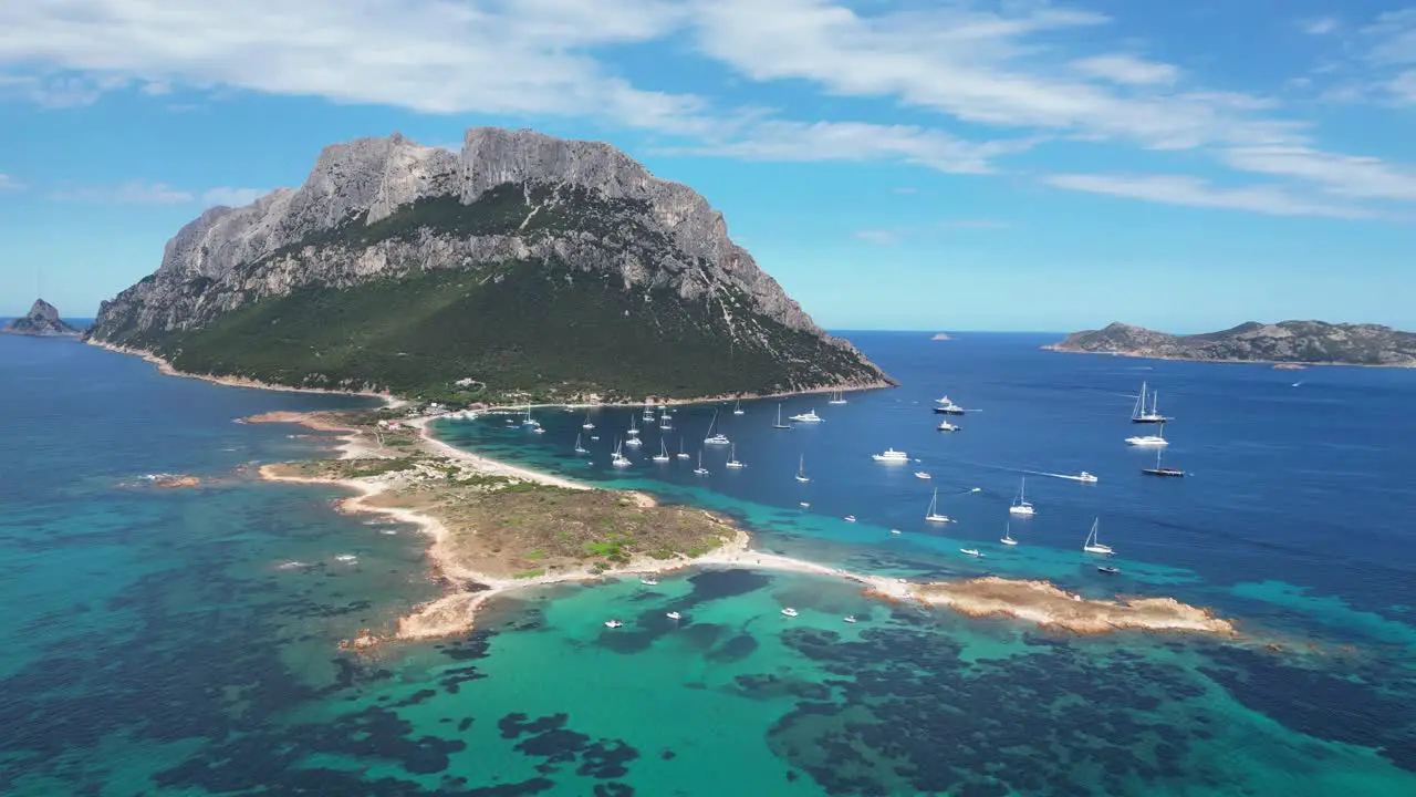 Tavolara Island surrounded by boats and blue sea during summer in Sardinia Italy Aerial 4k