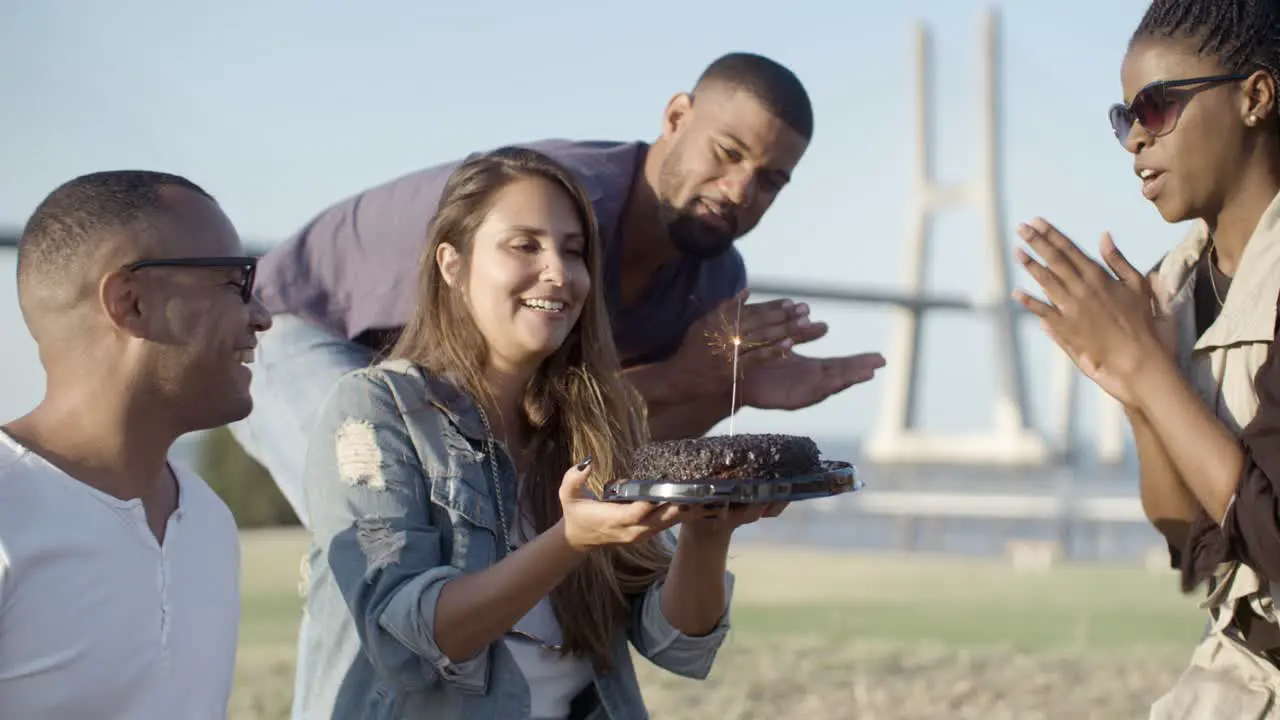 Smiling woman with long hair holding cake with sparkler