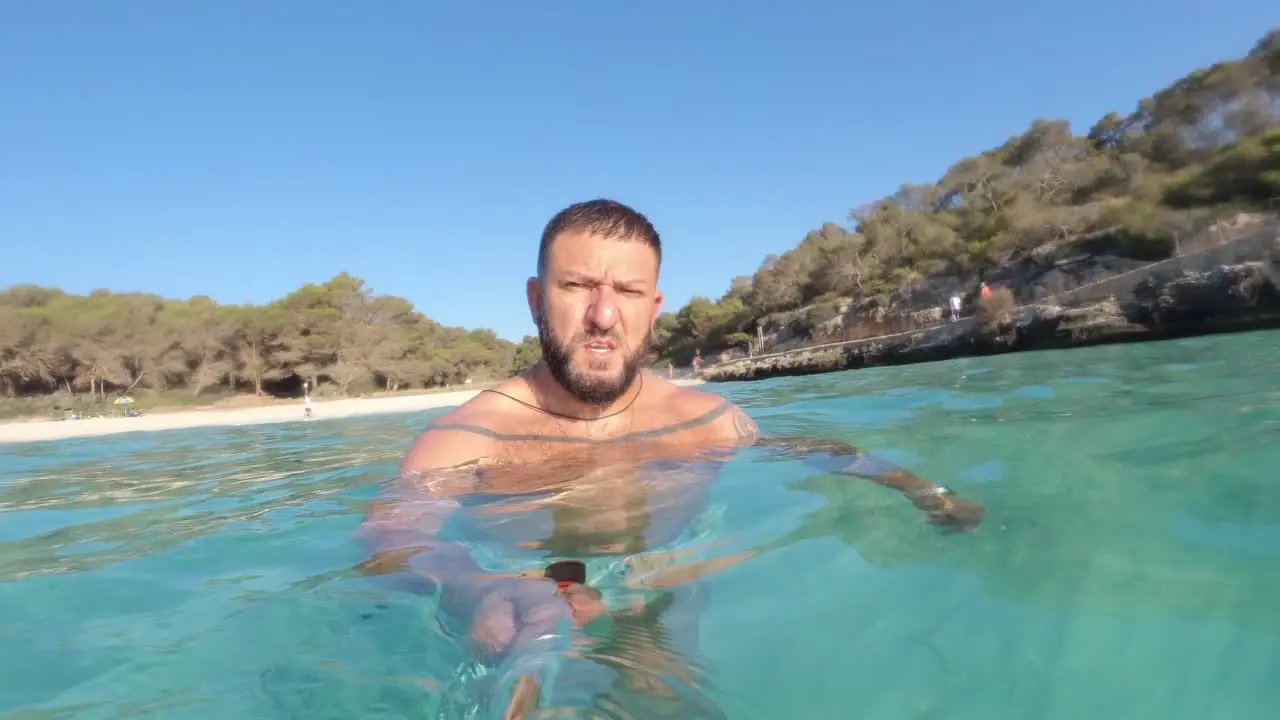 man swimming in a paradisiacal beach with an action camera