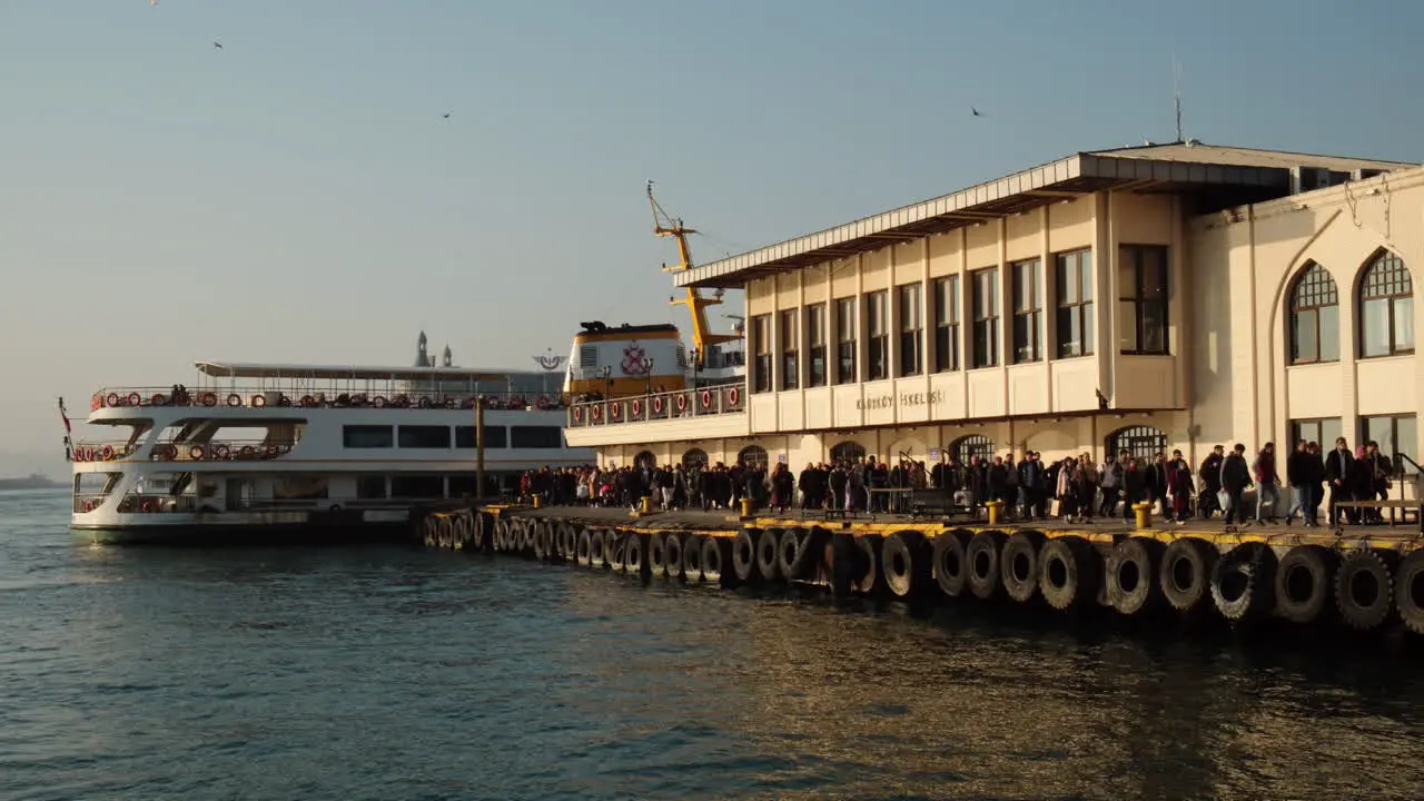 Crowd of people disembarking from the ferry docking in Istanbul Kadıköy under the warm sunset light