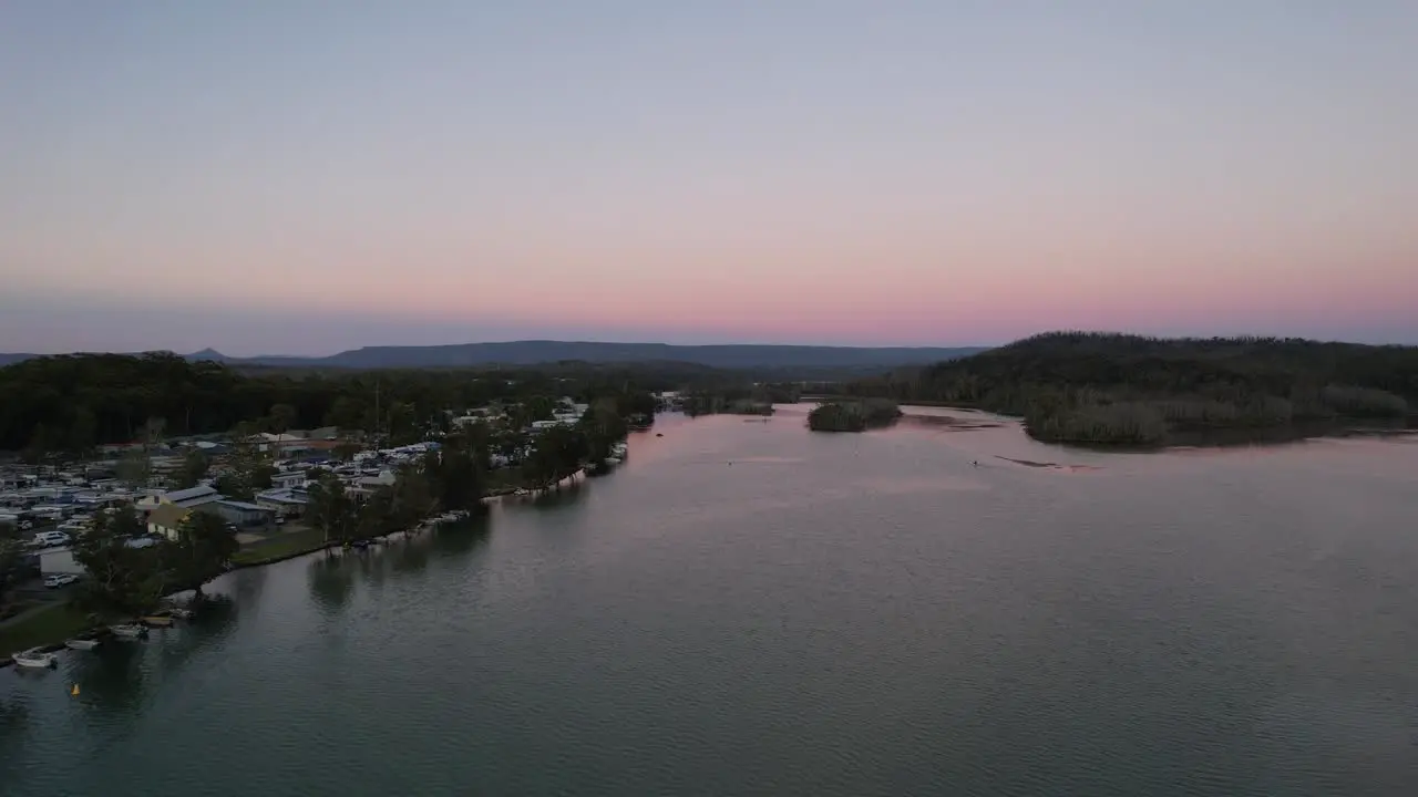 Aerial holiday town on river at sunrise pink sky Lake Conjola Australia