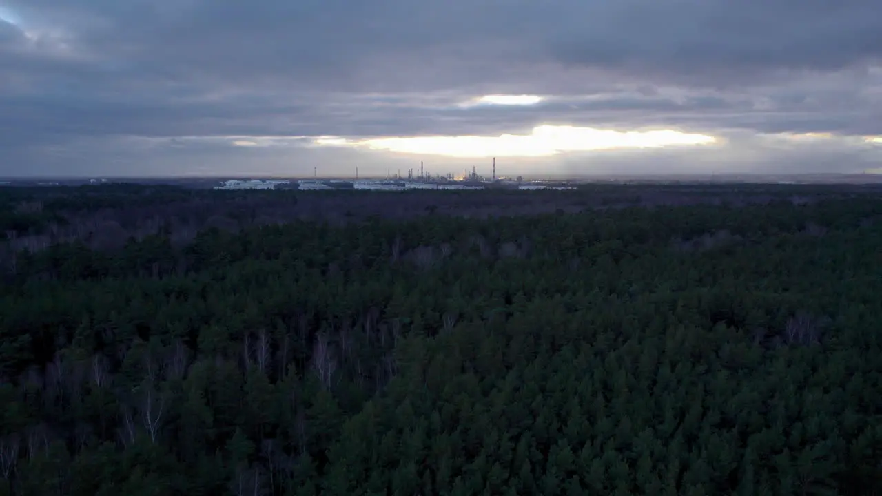 Aerial Flying Over Forest Landscape With Industrial Oil Storage Tanks In Background On Moody Cloudy Afternoon