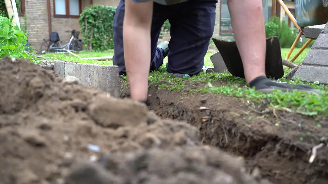 Gardener Building Stone Slab Wall Around Vegetable Garden Low Angle