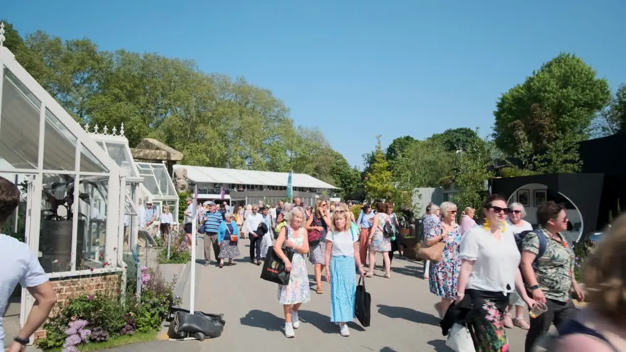 People walking through sculptures and greenhouse exhibits on a sunny day at the Chelsea flower show