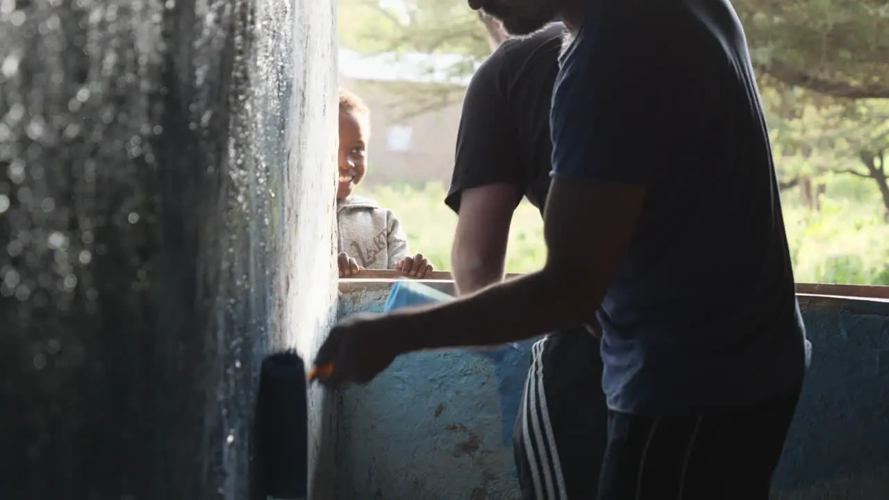 Two charity staff members paint inside wall of classroom