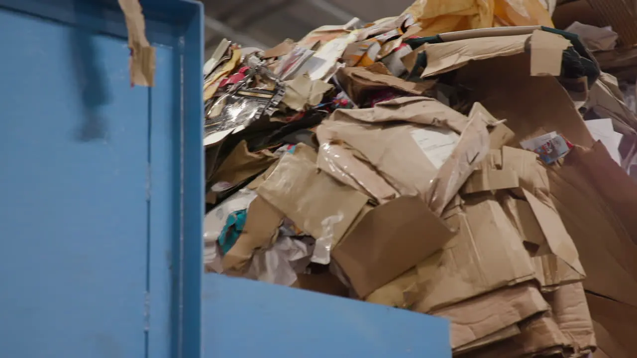 Excavator or Loader Bucket Scoops Up A Pile Of Cardboard Waste In Recycling Factory