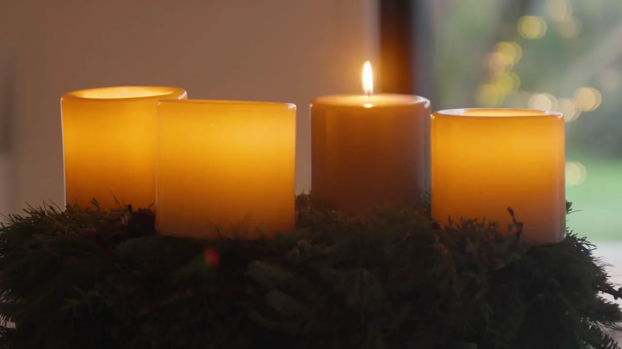 Three glowing candles on evergreen wreath festive ambiance