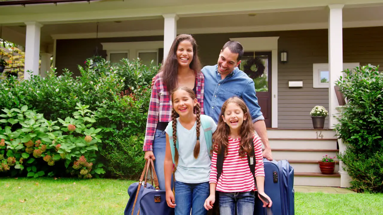 Portrait Of Family With Luggage Leaving House For Vacation