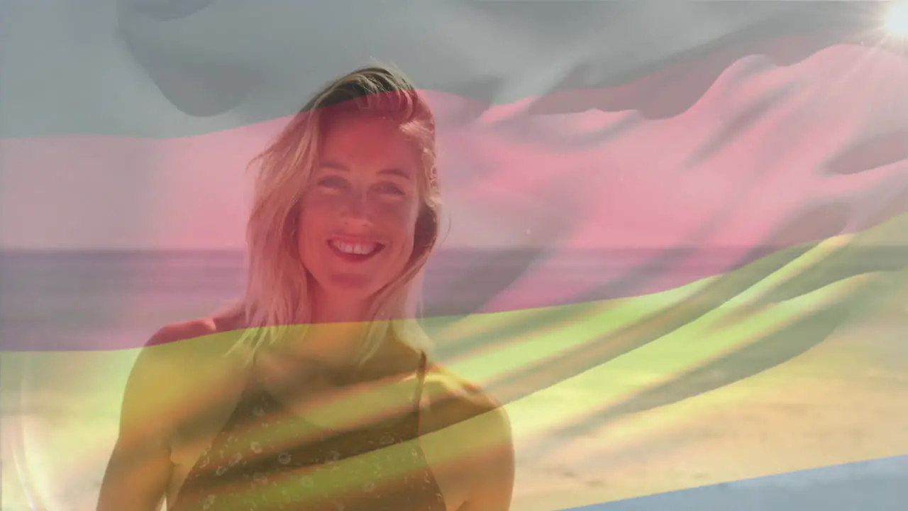 Animation of waving flag of germany over smiling caucasian woman standing against sea at beach