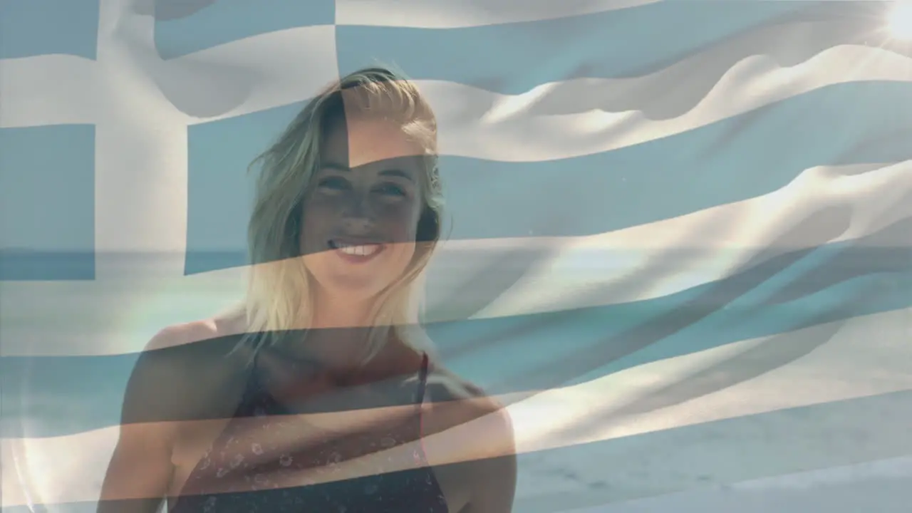 Animation of flag of greece waving over smiling caucasian woman standing against sea at beach